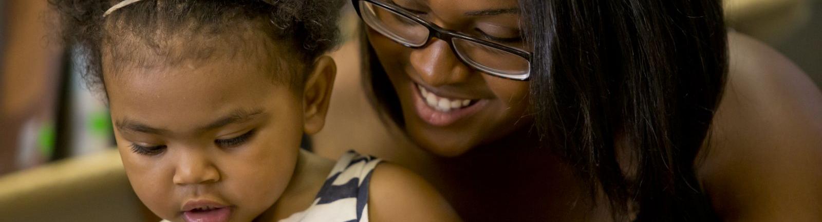an adult woman and infant girl reading together